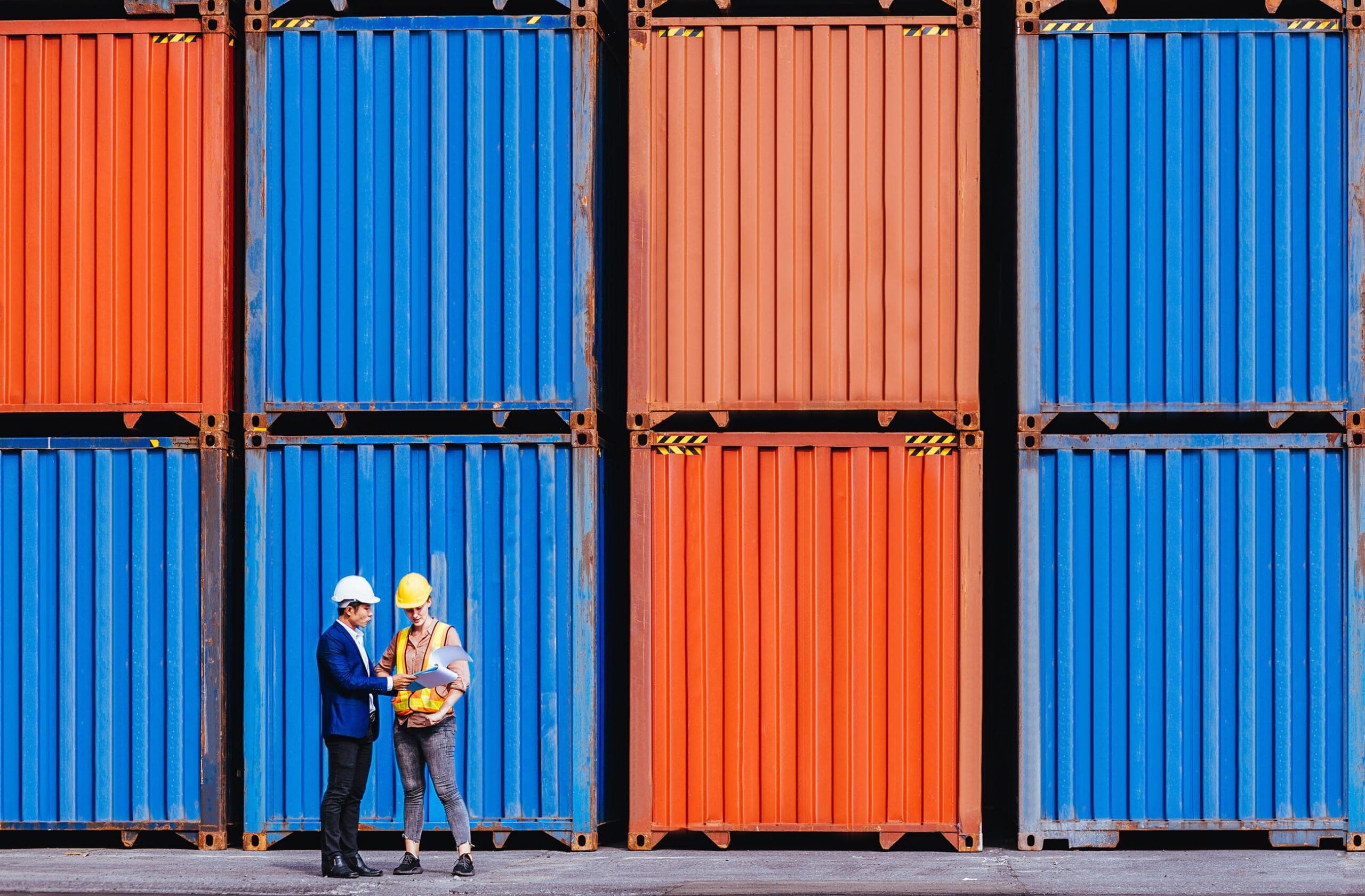 Two men standing in front of shipping containers